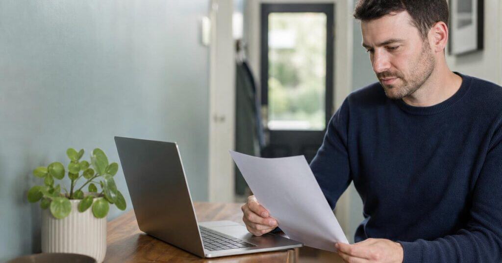 Person checking a Revenue letter against their laptop at home